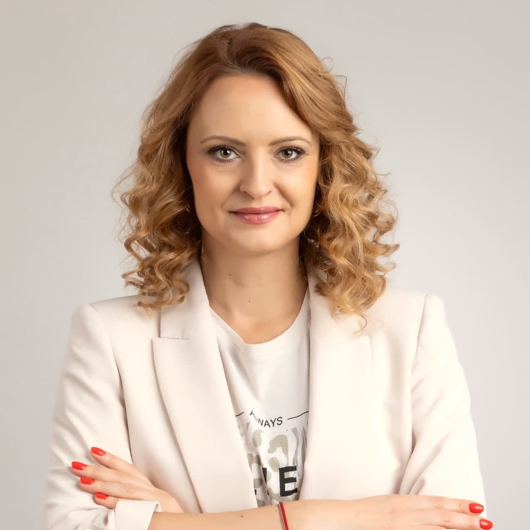 Anita Freimann in a white blazer, arms crossed